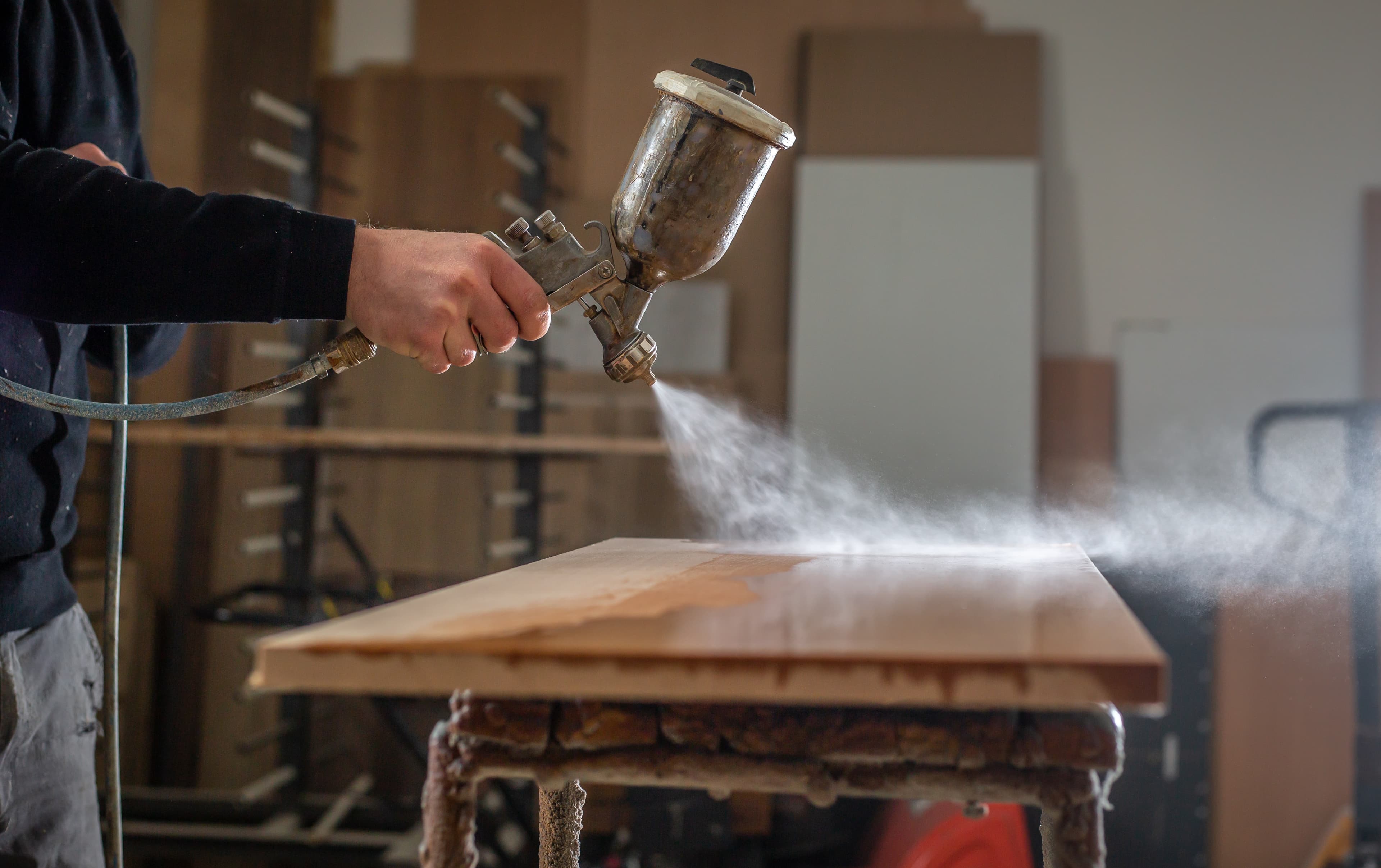 Man spray painting on a  piece of furniture